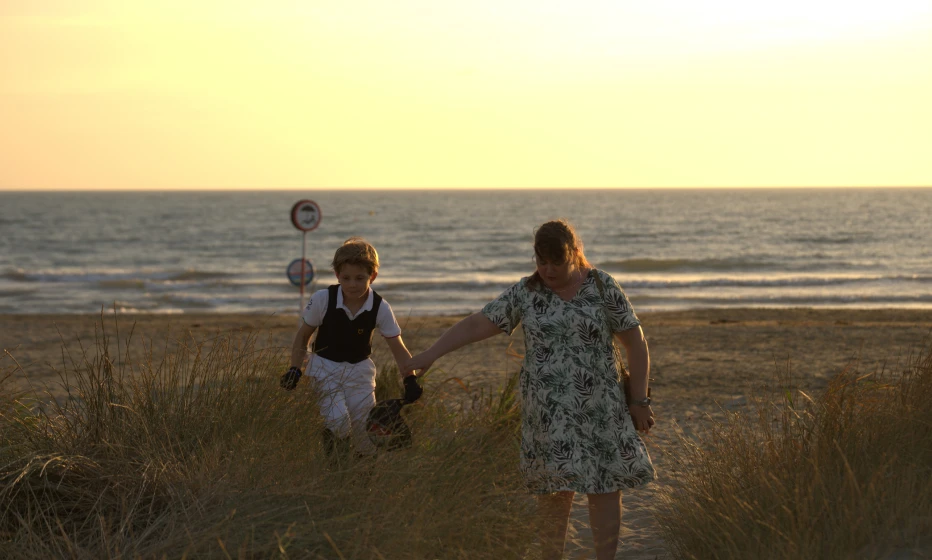 A mother and child on a beach at sunset.